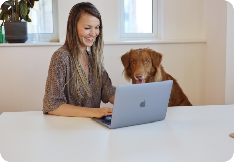 woman working on a laptop, dog sitting next to her
